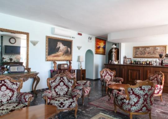 Salotto elegante con mobili antichi, dipinti e un angolo bar ben fornito.